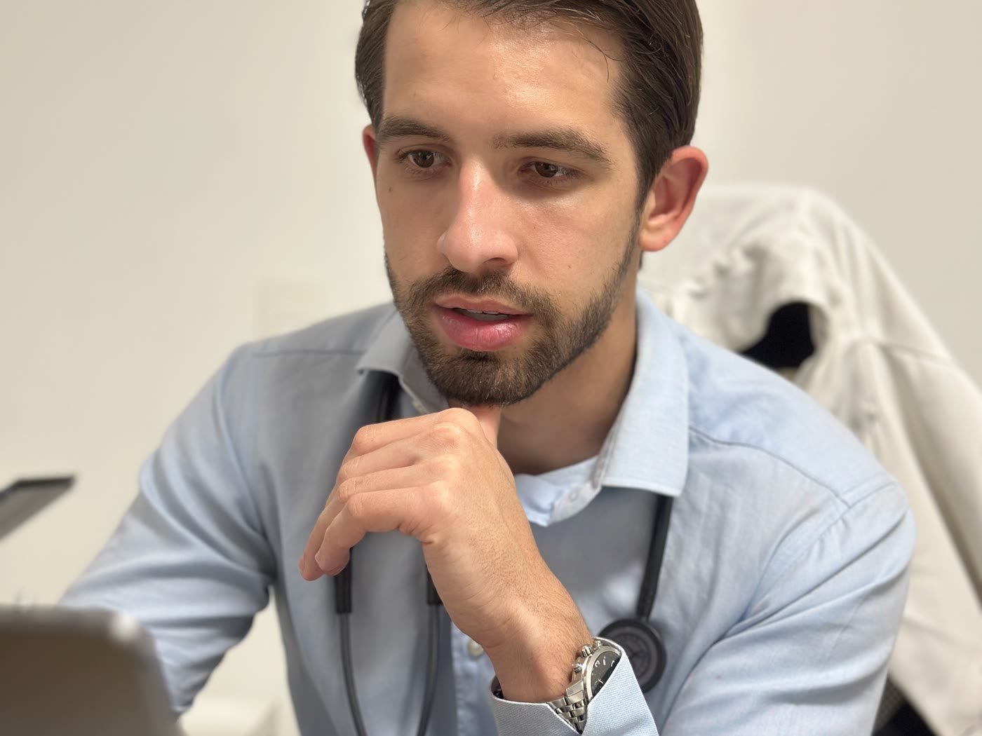 Dr. Jorge Madeiro, médico, no consultório, pensativo diante do computador durante avaliação de saúde hormonal masculina