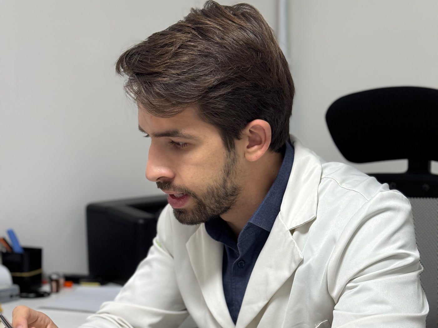 Dr. Jorge Madeiro no consultório, avaliando exames de sangue com o paciente